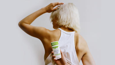Woman with her back to the camera holding Schmidt's Bergamot and Lime deodorant behind her